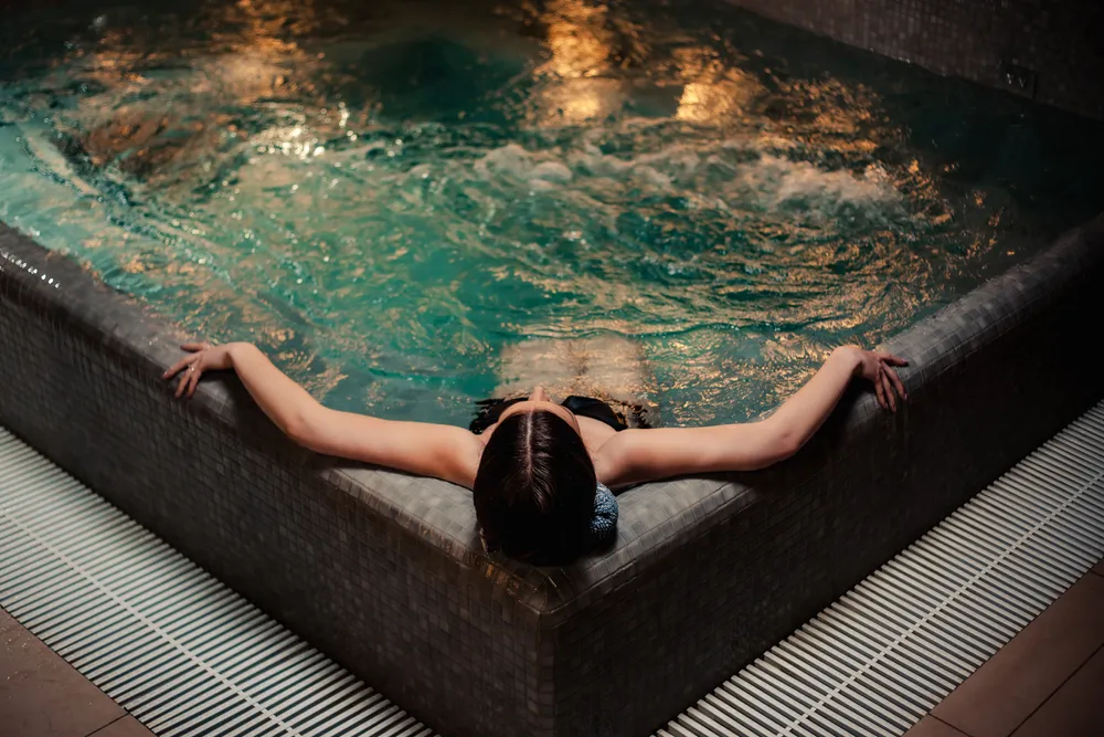 Kobieta odpoczywająca w jacuzzi z widokiem na taflę wody