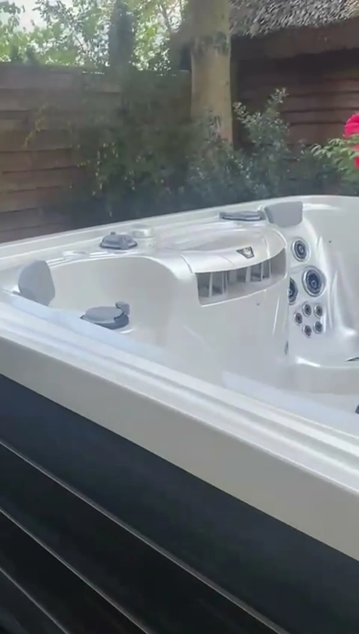 Jacuzzi Marquis ustawione w ogrodzie przy drewnianym domu