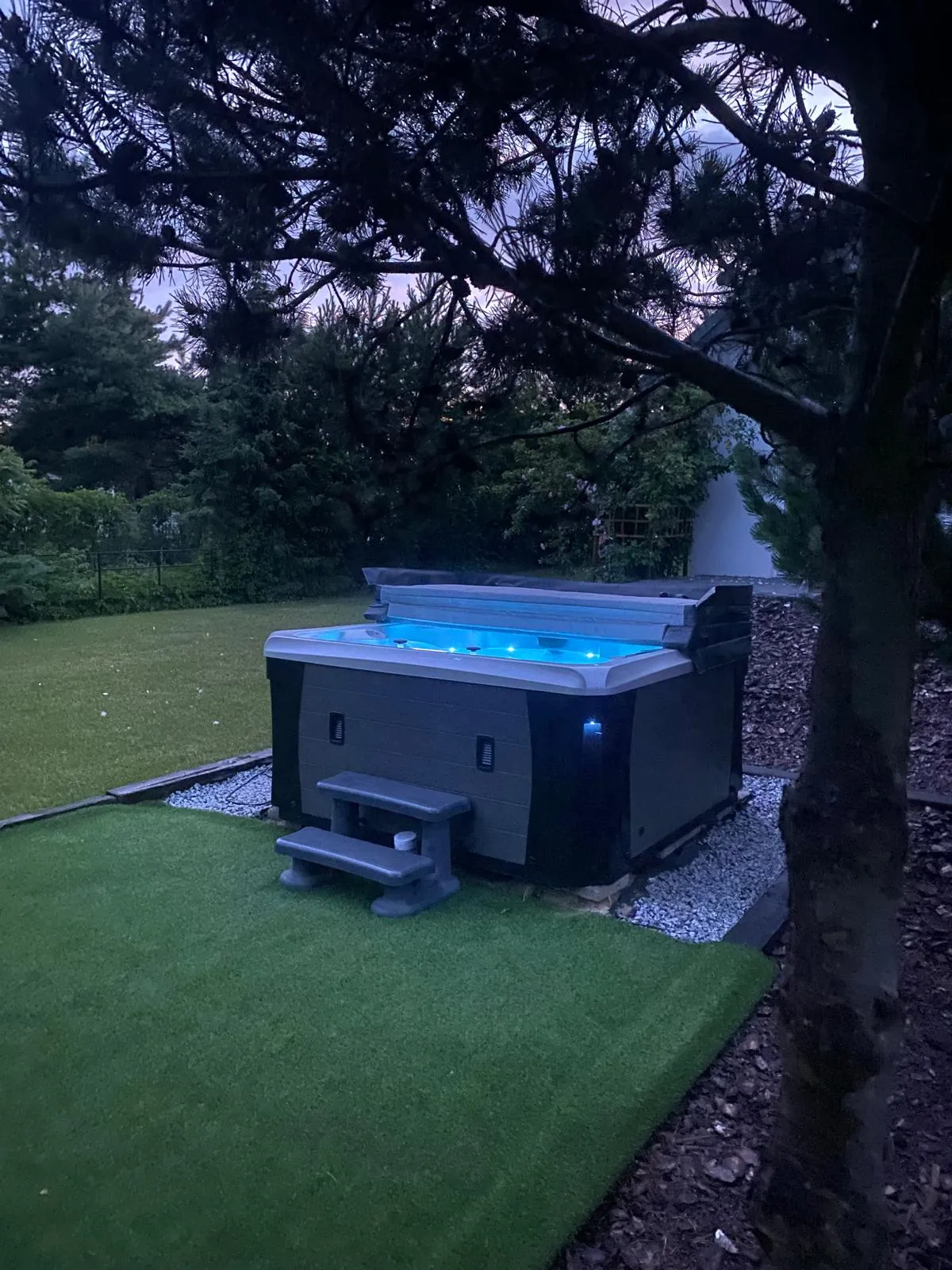 Jacuzzi z podświetleniem LED w ogrodzie o zmierzchu